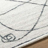 Close-up of the Sabah Area Rug showing its off-white base and light silver geometric line pattern and hand-tufted texture. Texture