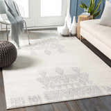 Living room scene with Wakita Light Gray Tribal Rug, white sofa, gray pouf, and light wood floors. Roomscene-Rectangle
