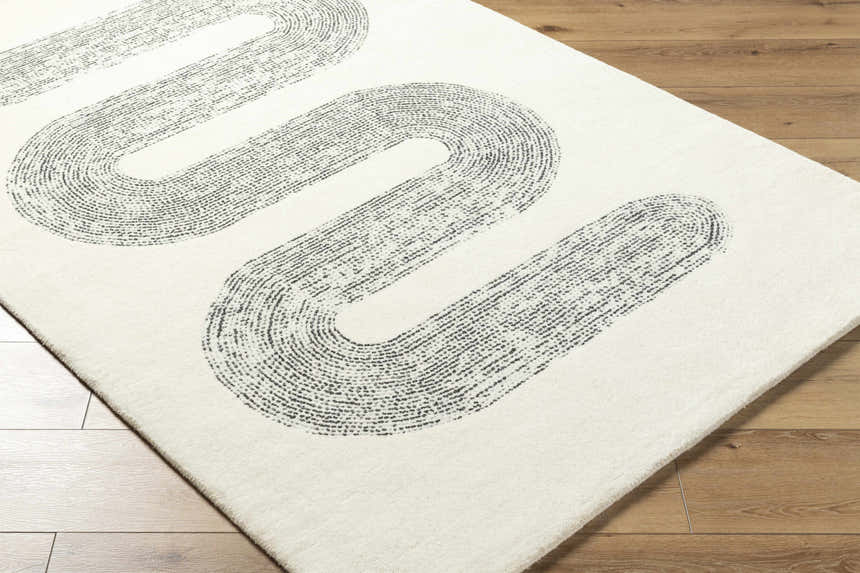 Close-up of the Saura Wool Area Rug. Ivory rug with a contemporary charcoal loop design on a wood floor. Corner