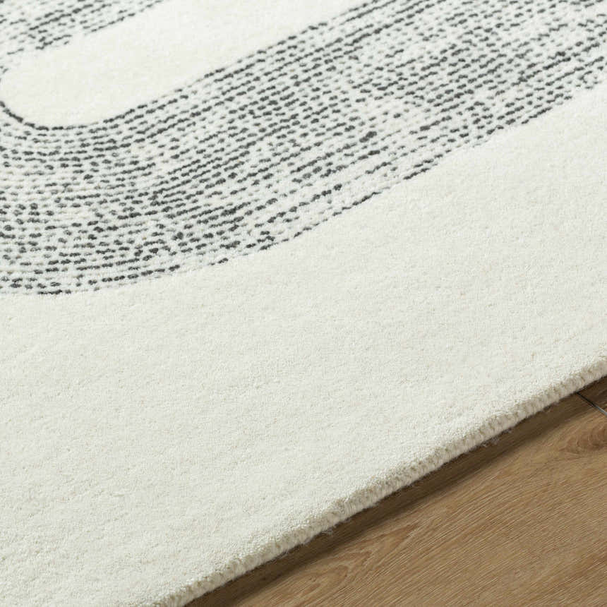 Close-up of the Saura Wool Area Rug. Features charcoal and ivory colors, hand-tufted texture, and contemporary style. Texture