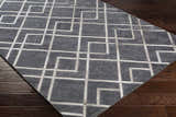 Close-up of the Taclobo Area Rug showing a gray viscose rug with a geometric light gray pattern on dark wood floors. Corner