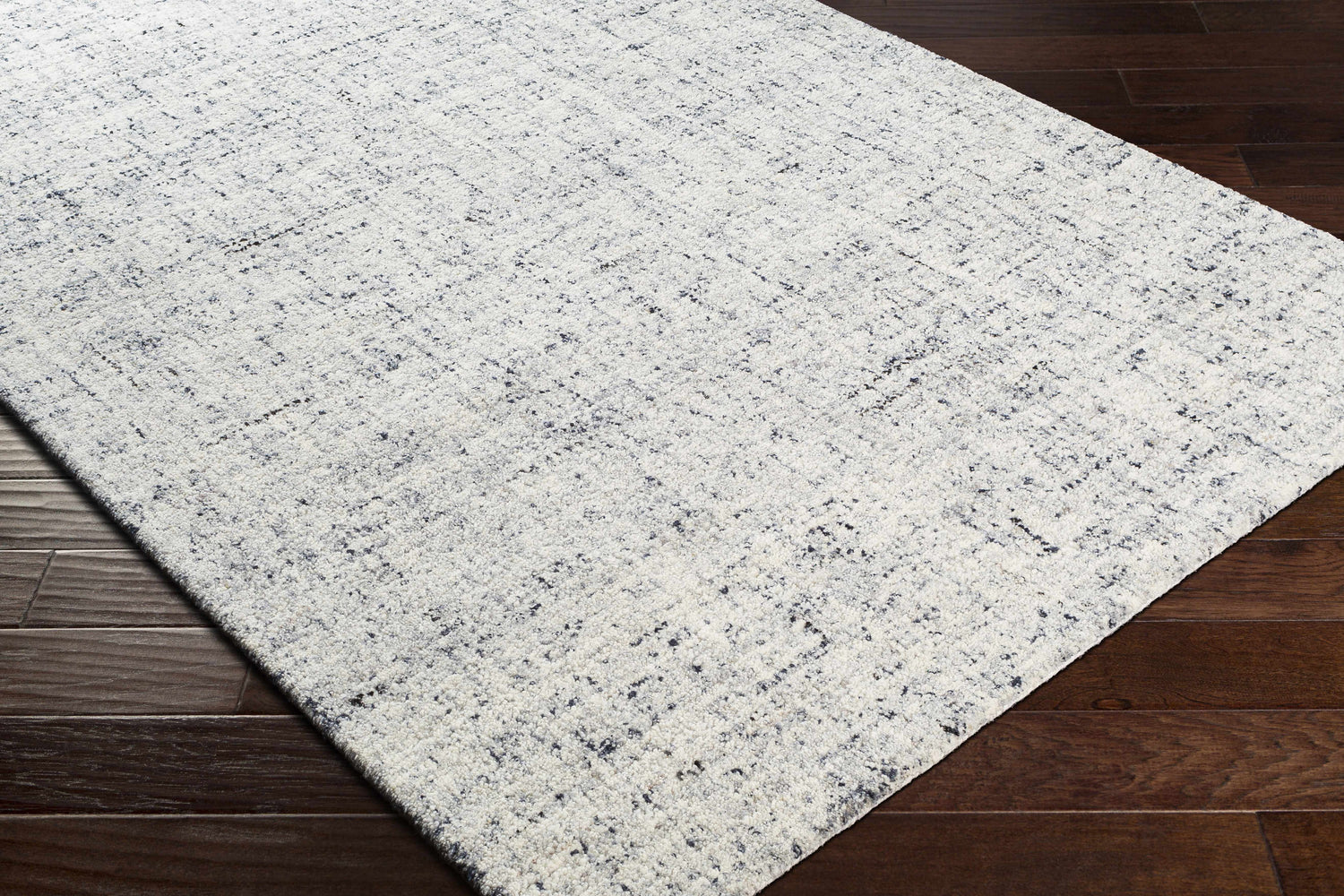 Close-up of the hand-tufted Tanana Area Rug. Cream wool rug with a subtle black and gray contemporary design. Corner
