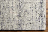 Close-up of the Tanana Area Rug. Cream wool rug with a subtle black and gray contemporary design. Hand-tufted texture. Corner