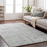 Living room scene with a Tanana Area Rug in cream and black, complementing the neutral sofa and wood floors. Roomscene-Rectangle