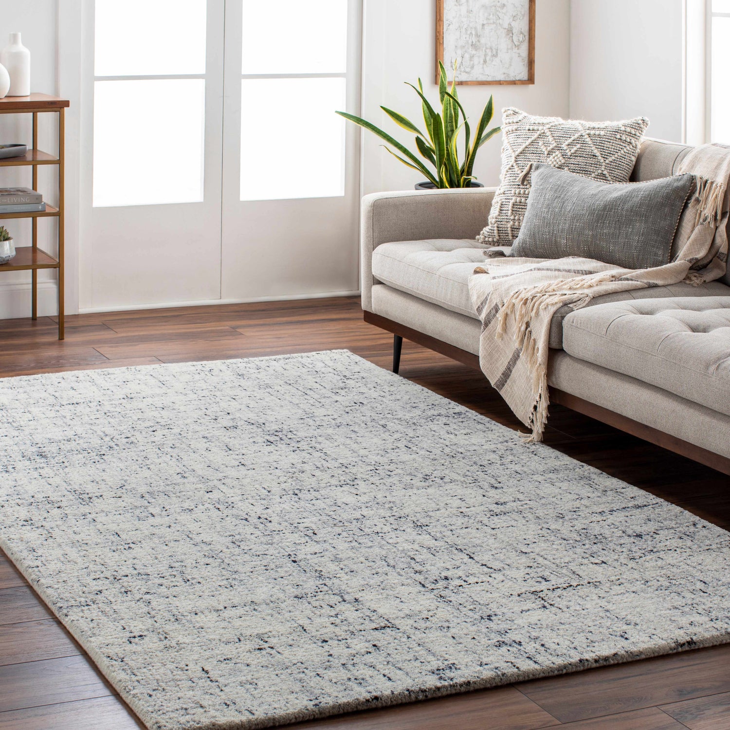 Living room scene with a Tanana Area Rug in cream and black, complementing the neutral sofa and wood floors. Roomscene-Rectangle