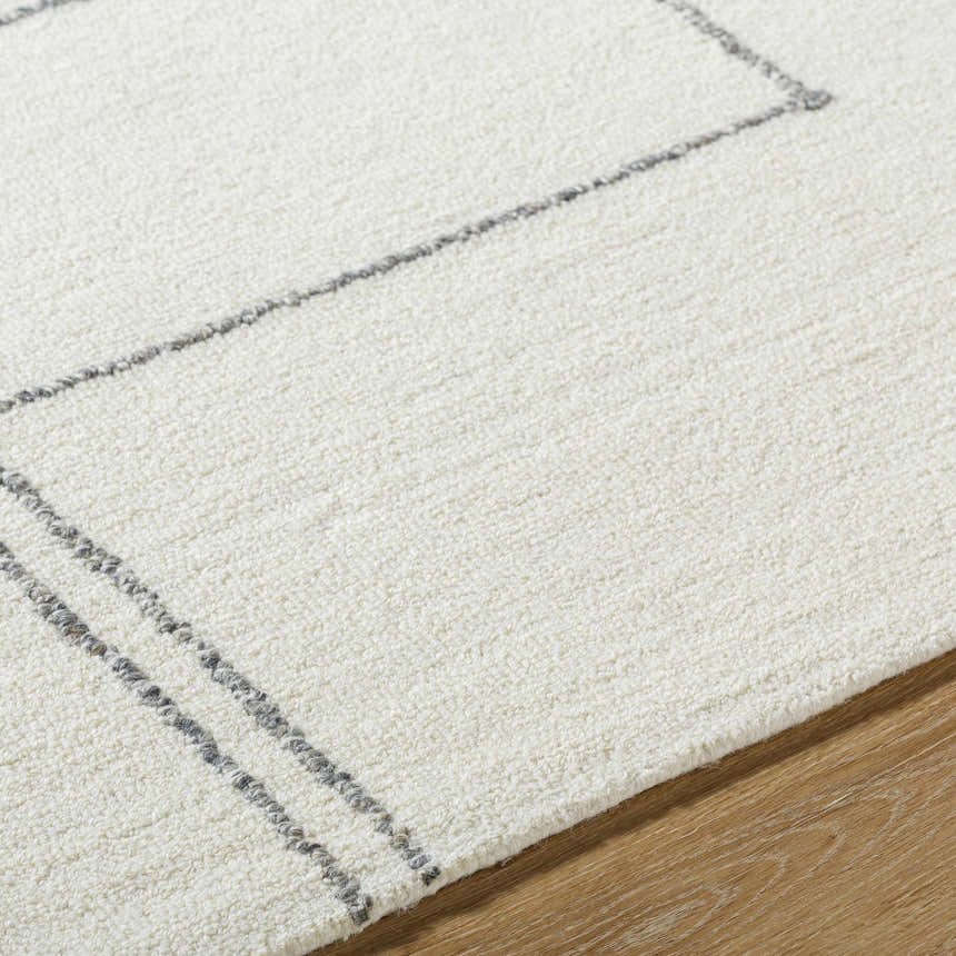 Close-up of the Truma Area Rug. Off white wool rug with a light silver geometric pattern and soft, textured pile. Texture
