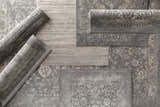 Close-up of gray Benavides Updated Traditional Tibetan Rugs in various shapes and sizes showing detailed floral patterns. Styleshot