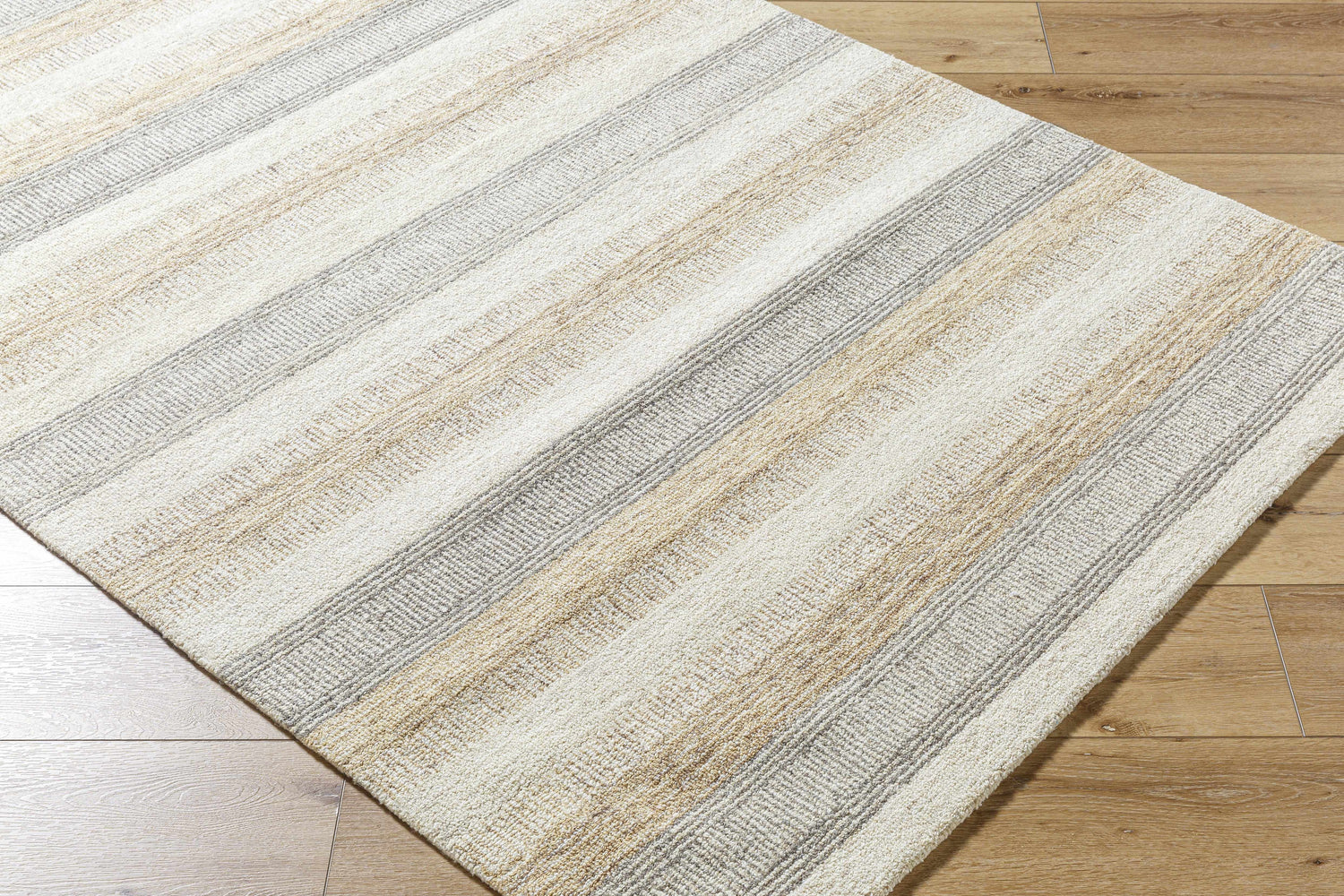 Close-up of the hand-tufted Touca Area Rug. Ash, light silver, silver gray, and warm gray stripes on a wool rug. Corner
