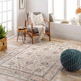 Living room scene with a beige Temelec Area Rug, wood chair, teal pouf, and natural light from a window. Roomscene-Rectangle