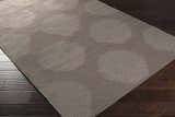 Close-up of the hand woven Tensed Area Rug. Charcoal wool rug with a contemporary circle and stripe design. Corner