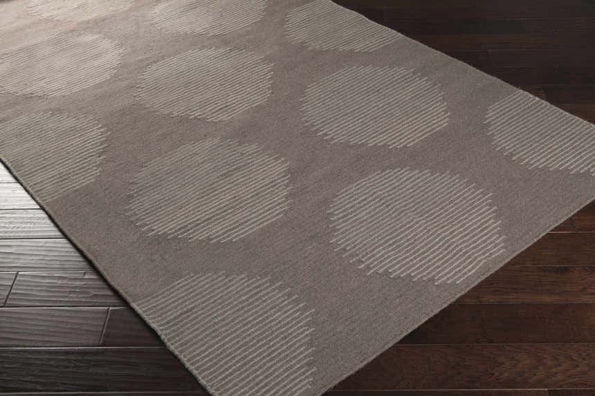 Close-up of the hand woven Tensed Area Rug. Charcoal wool rug with a contemporary circle and stripe design. Corner