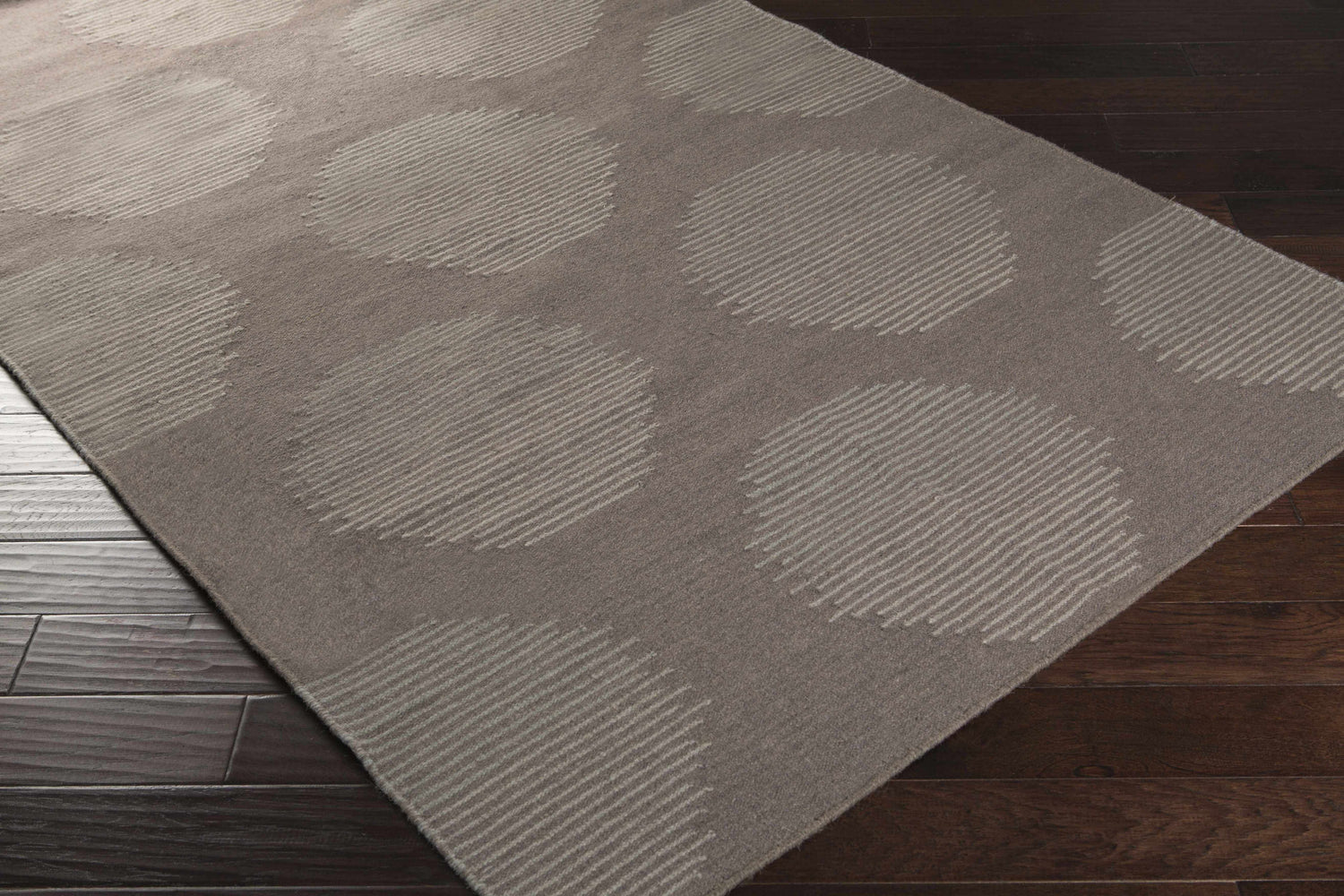 Close-up of the hand woven Tensed Area Rug. Charcoal wool rug with a contemporary circle and stripe design. Corner