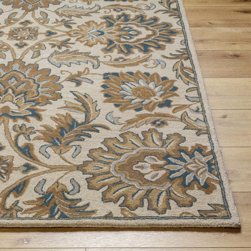 Close-up of the hand-tufted Teom Area Rug. Beige wool rug with a traditional floral pattern in camel, brown, and blue. Front