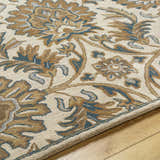 Close-up of the hand-tufted Teom Area Rug. Beige wool rug with a traditional floral pattern in camel, clay, and dark gray. Texture
