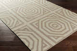 Close-up of the Terlton Ivory Greek Geometric Rug, a hand-woven wool rug with taupe geometric patterns on a dark wood floor. Corner