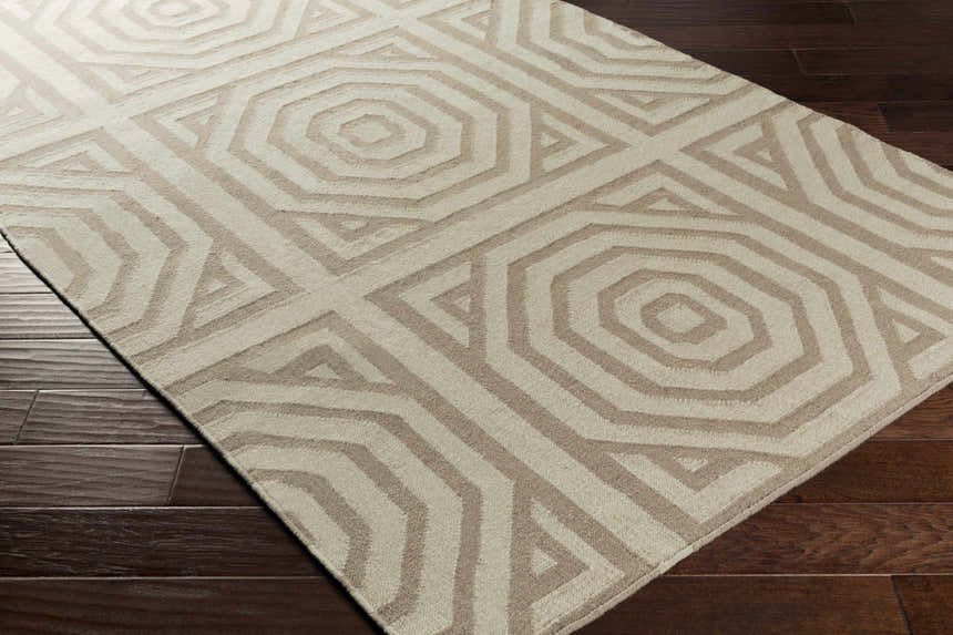 Close-up of the Terlton Ivory Greek Geometric Rug, a hand-woven wool rug with taupe geometric patterns on a dark wood floor. Corner