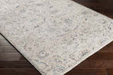 Close-up of the Ternate Area Rug showing its cream, denim, and brick red traditional pattern on dark wood floors. Corner