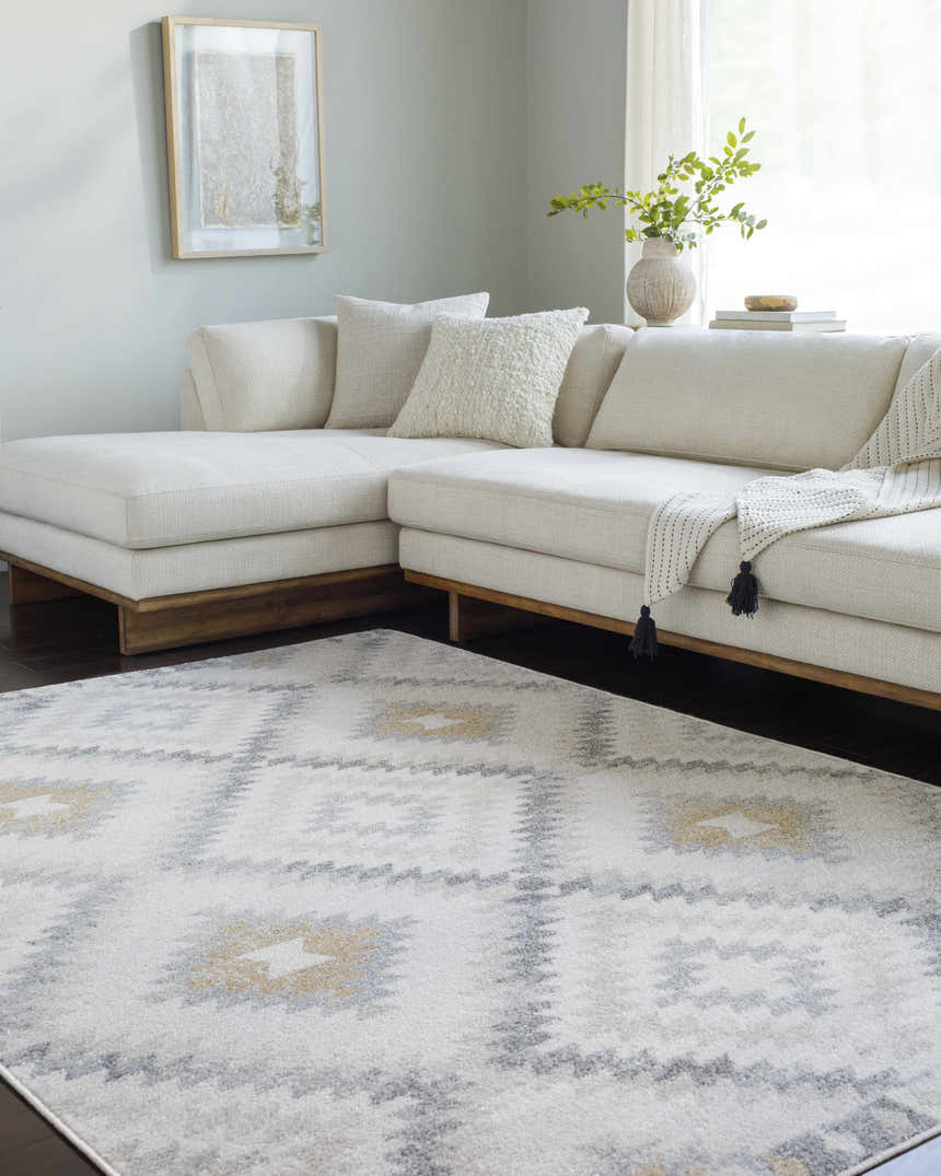 Living room scene with a cream sectional sofa and a Southwestern style Tyipa Area Rug in charcoal, cream, gray, and mustard. Roomscene-Rectangle