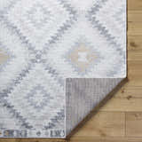 Close-up of Tyipa Area Rug showing Southwestern pattern in charcoal, cream, gray, mustard, and peach on wood floor. Fold