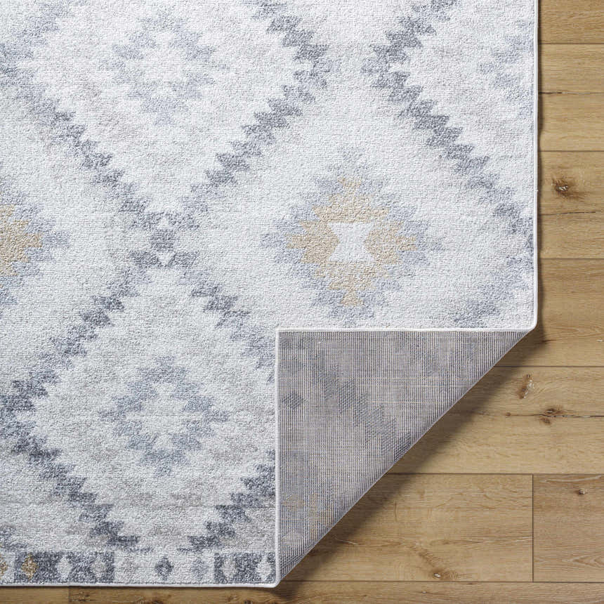 Close-up of Tyipa Area Rug showing Southwestern pattern in charcoal, cream, gray, mustard, and peach on wood floor. Fold