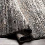 Close-up of Tigaon Luxe Thick Area Rug showing its abstract pattern, texture, and colors: gray, cream, tan, and charcoal. Fold