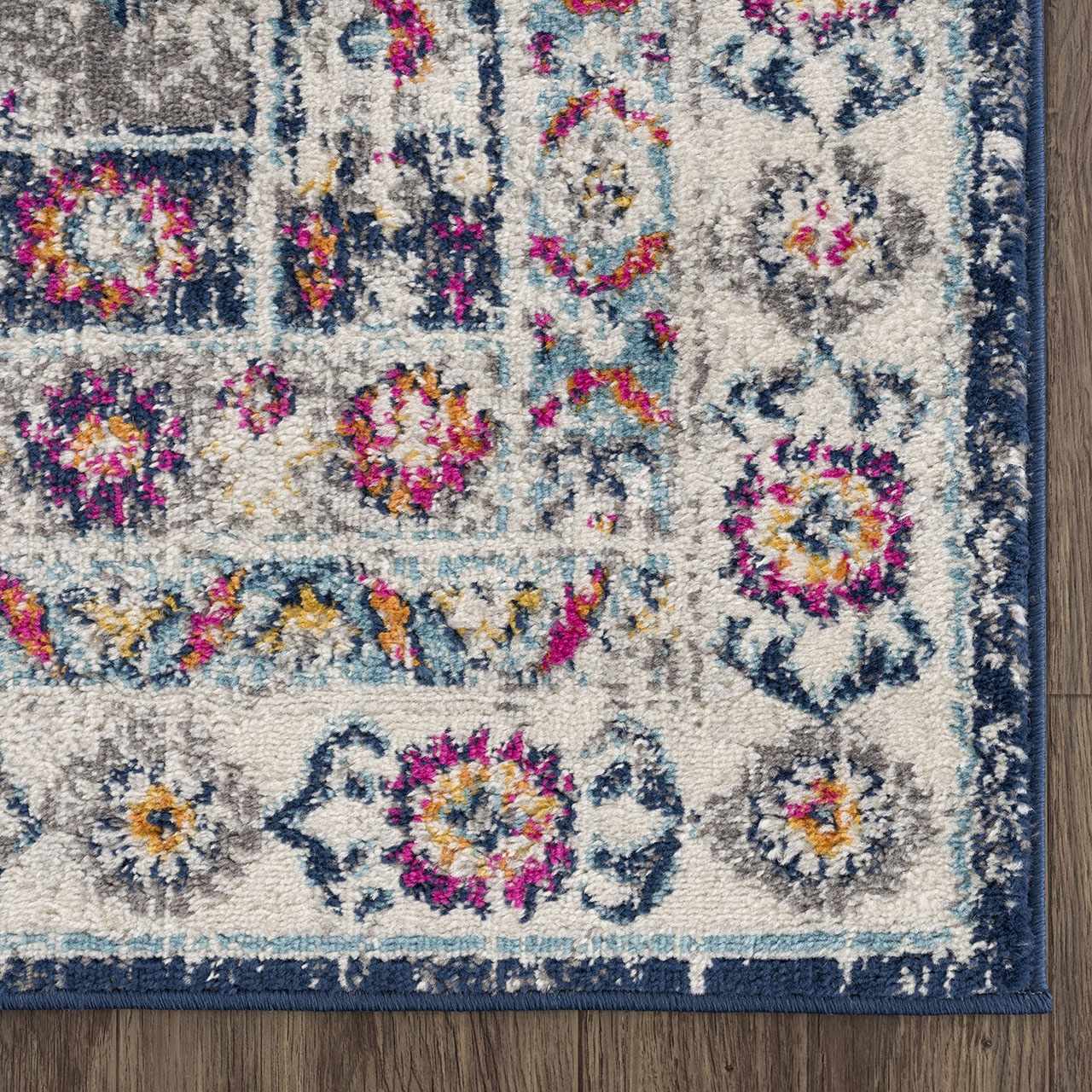 Close-up of the Tigrim Beige 2306 Area Rug. Features a floral, bohemian pattern in beige, ivory, navy, pink, and yellow. Corner