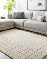 Living room scene with a gray sectional sofa and a Toshi Beige Area Rug with a geometric diamond pattern. Roomscene-Rectangle