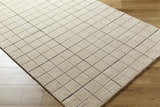 Close-up of the Toshi Beige Area Rug. Hand-tufted wool rug with a contemporary square pattern in tan, gray, and black. Corner