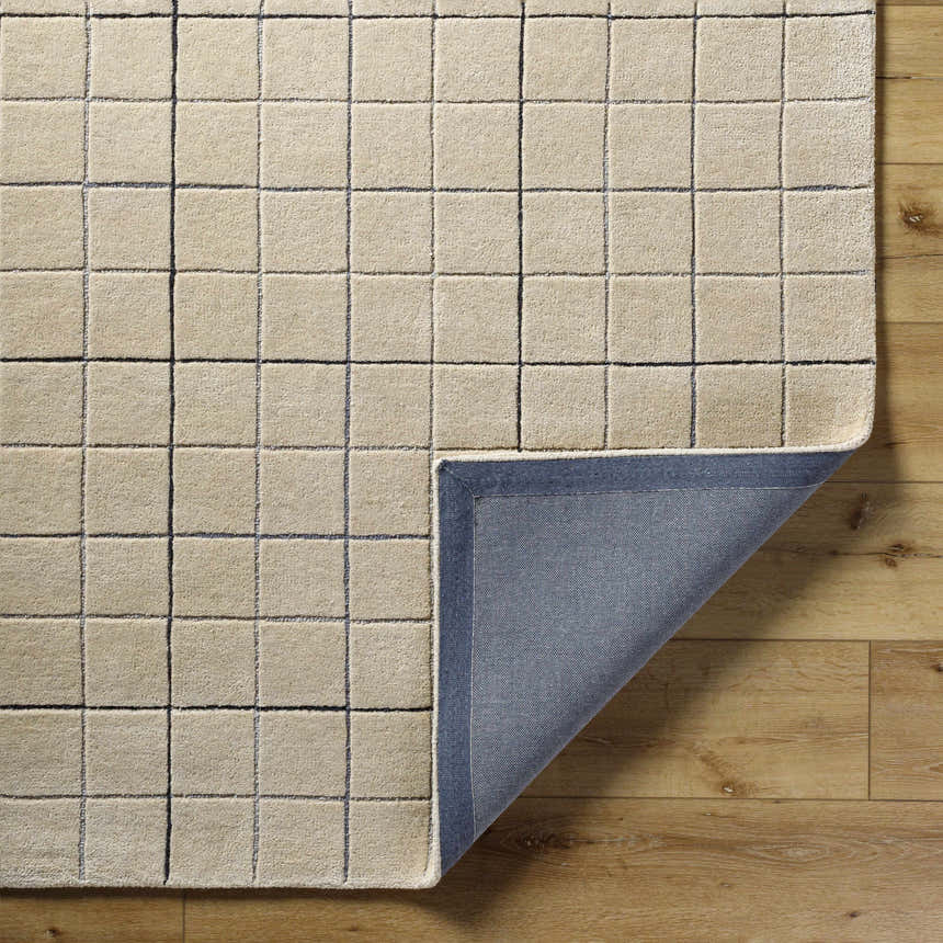 Close-up of the Toshi Beige Area Rug. Hand-tufted wool rug with a contemporary grid pattern in beige, black, and gray. Fold