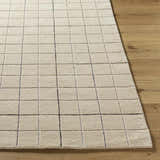 Close-up of the Toshi Beige Area Rug showing its geometric square pattern and soft, textured wool on hardwood floor. Front