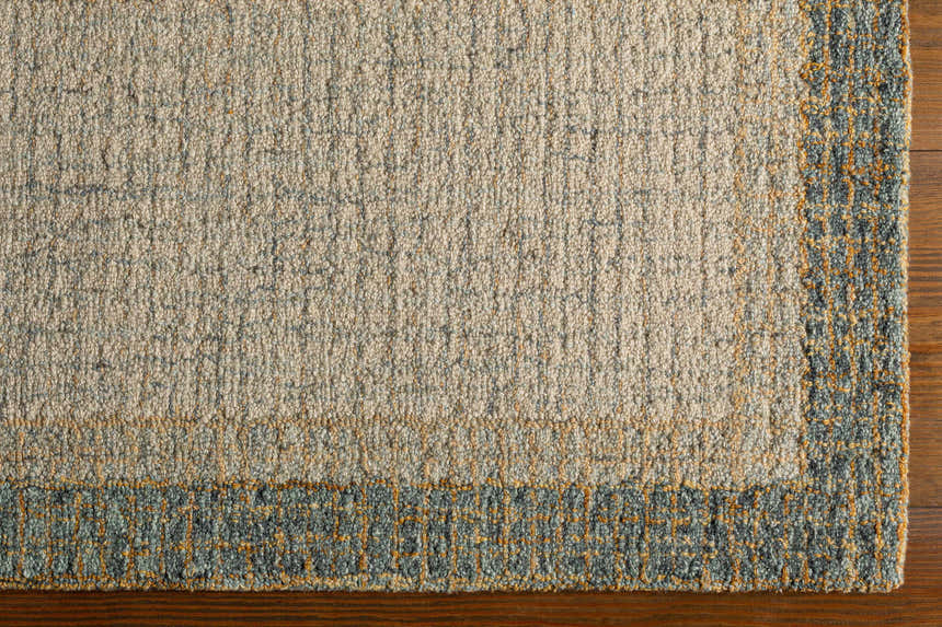 Close-up of the hand-tufted Tandayag Area Rug. Features cream, sage, and tan wool with a contemporary striped design. Corner