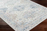 Close-up of the Tana Washable Area Rug. Traditional farmhouse style with arctic stone, blue, and nutmeg hues. Corner
