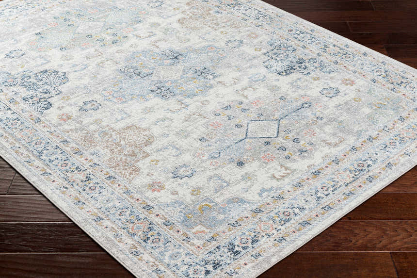 Close-up of the Tana Washable Area Rug. Traditional farmhouse style with arctic stone, blue, and nutmeg hues. Corner