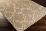 Close up of the Toledo Area Rug, a beige rug with a light beige quatrefoil pattern on dark wood floors. Corner