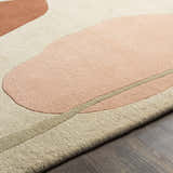 Close-up of the Tomingad Area Rug. Hand-tufted wool rug with geometric shapes in brick red, dusty pink, oatmeal, and taupe. Texture