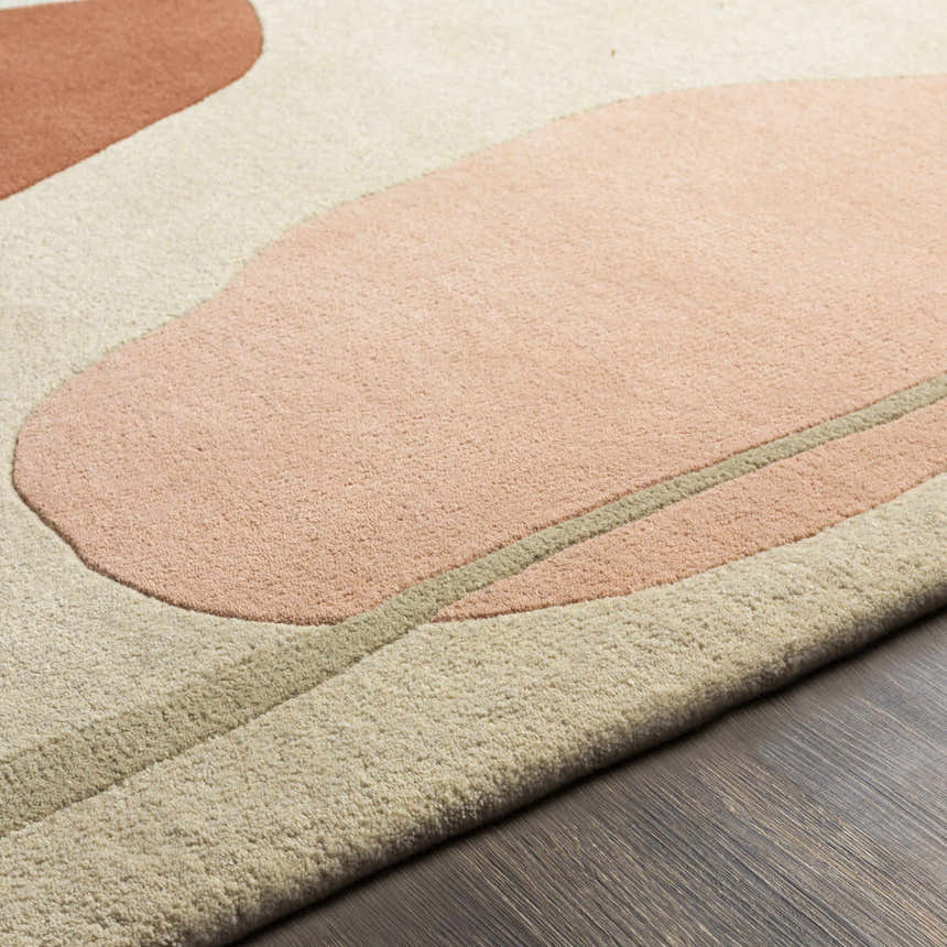 Close-up of the Tomingad Area Rug. Hand-tufted wool rug with geometric shapes in brick red, dusty pink, oatmeal, and taupe. Texture