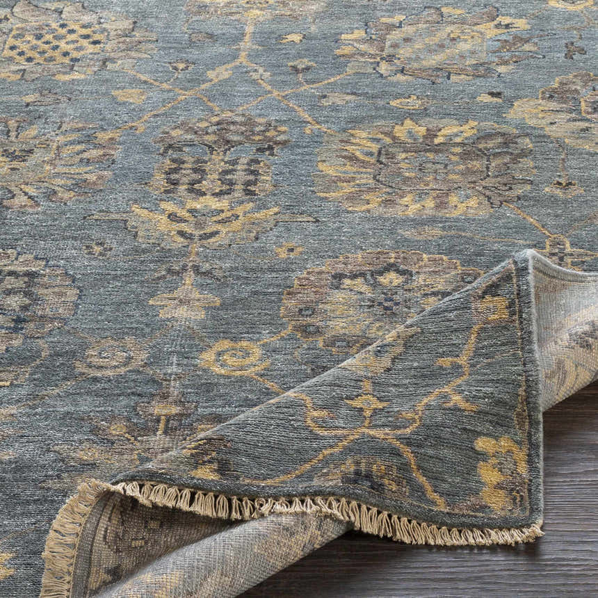 Close-up of the hand-knotted Toquerville Premium Rug. Aqua, charcoal, and wheat colors with a traditional floral pattern. Fold