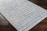 Close-up of the hand-woven Totolan Area Rug. Beige, denim, and black jute stripes on dark wood floor. Coastal Grandmother style. Corner