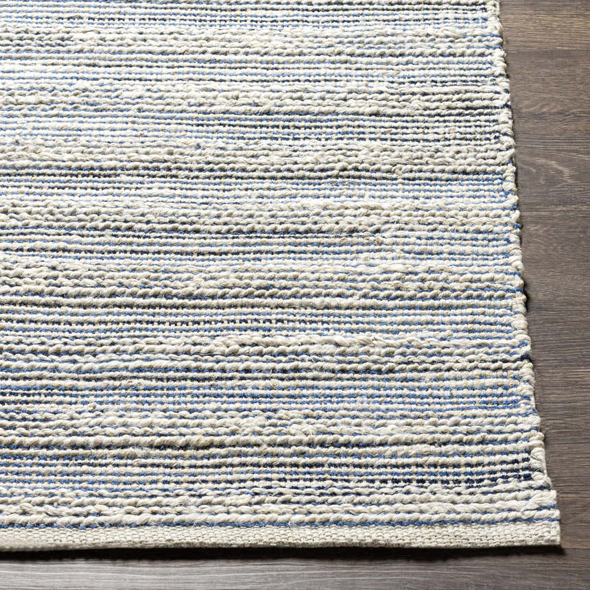 Close-up of Totolan area rug showing beige jute with denim and black stripes. Hand-woven texture detail. Front