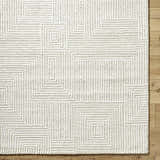 Close up of the hand tufted Tyrus Area Rug. Ash, light silver, and off white geometric pattern. 100% wool texture. Corner