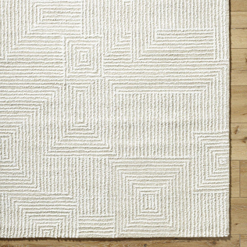 Close up of the hand tufted Tyrus Area Rug. Ash, light silver, and off white geometric pattern. 100% wool texture. Corner