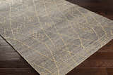 Close-up of the Tregarth Area Rug showing jute construction and geometric diamond pattern on dark wood flooring. Corner