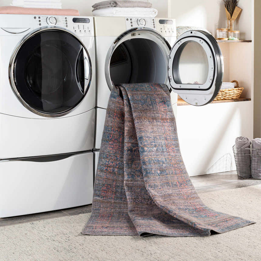 Troupsburg Washable Area Rug in laundry room being pulled from dryer. Blue, pink, and tan oriental rug. Washing-Machine
