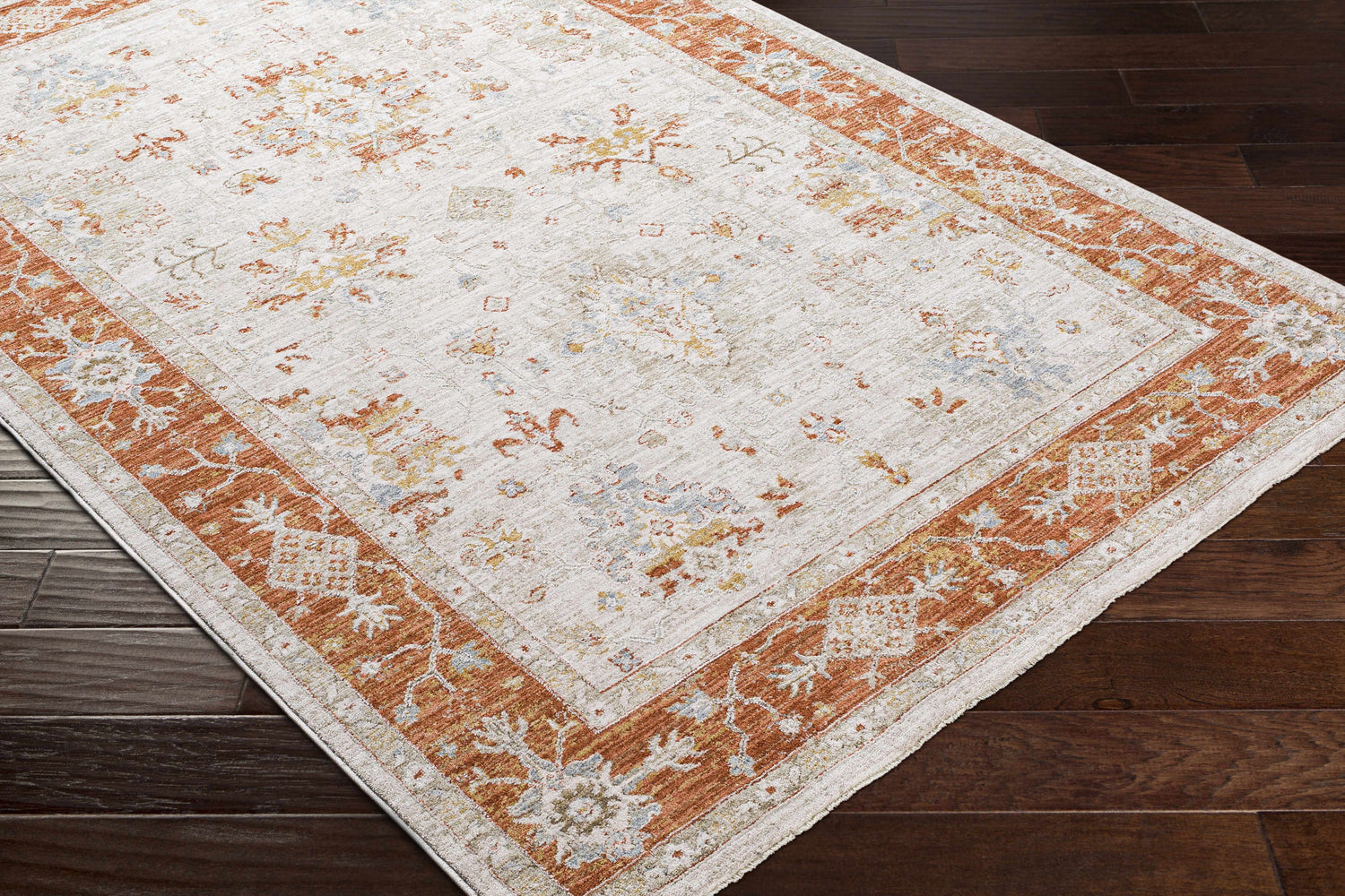 Tsawwassen Thick Luxe Area Rug close-up. Brick red border, light beige center with charcoal, denim, and mustard floral accents. Corner