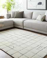 Living room scene with a light gray sectional sofa and the Tuuka Pearl Area Rug with a geometric grid pattern. Roomscene-Rectangle