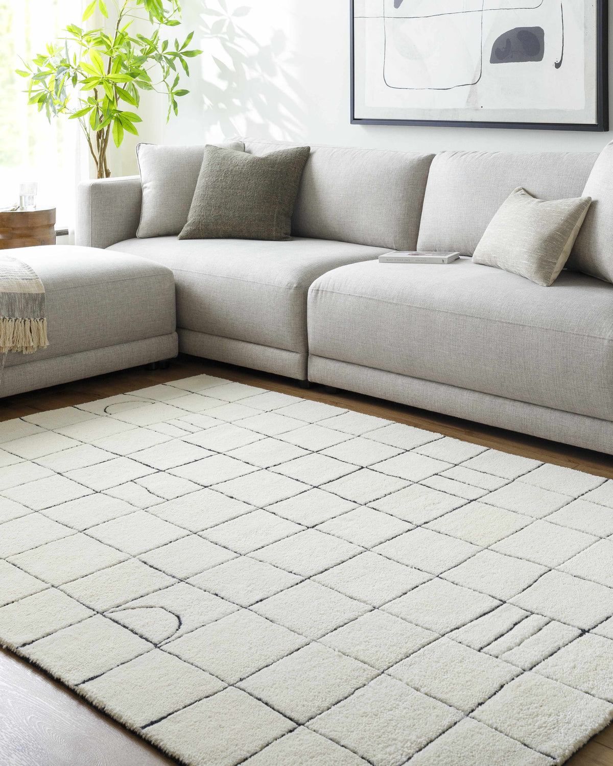 Living room scene with a light gray sectional sofa and the Tuuka Pearl Area Rug with a geometric grid pattern. Roomscene-Rectangle