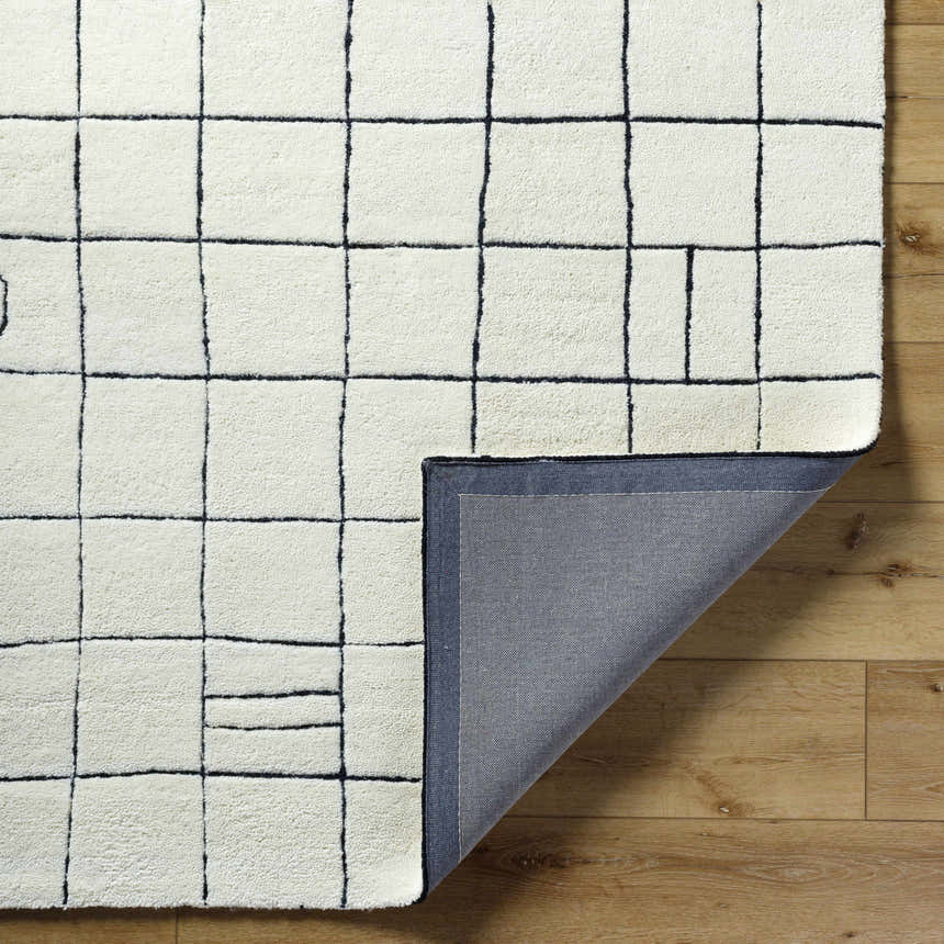 Close-up of Tuuka Pearl Area Rug showing its pearl color, grid pattern, hand-tufted texture, and the rug's backing. Fold