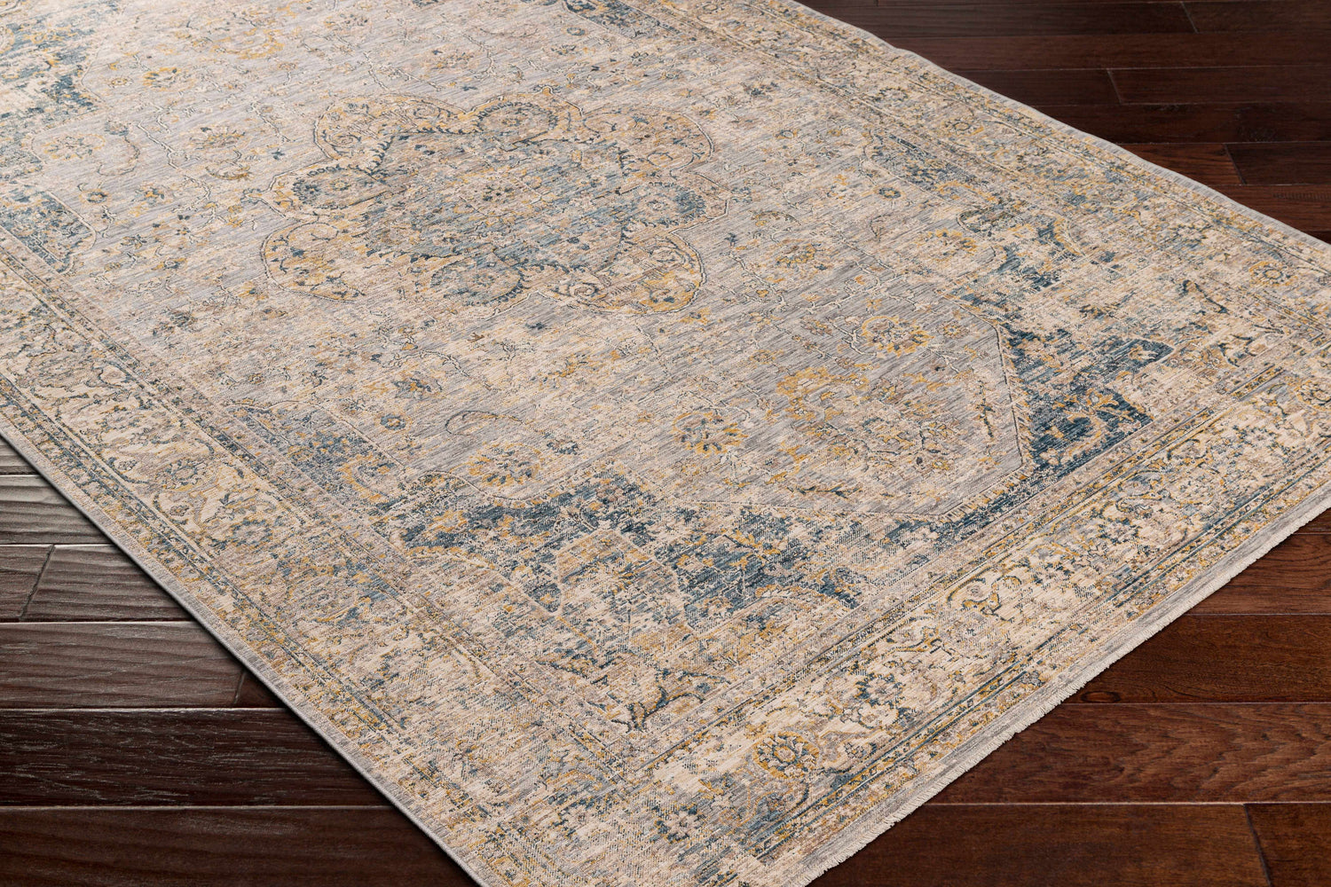 Close up of the Tuganay Luxe Performance Rug in beige, blue, and mustard on dark wood floors. Bohemian style rug. Corner
