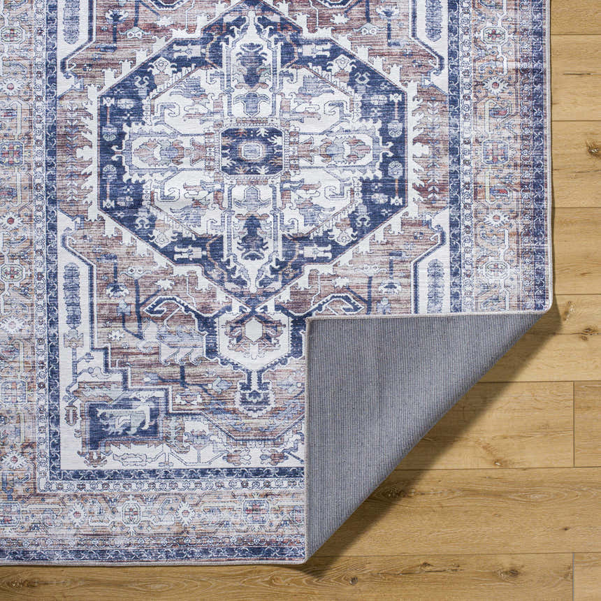 Close-up of the Terri Washable Area Rug, showcasing its traditional beige, blue, and red pattern and machine-woven texture. Fold