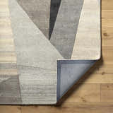 Close-up of the Toril Modern Wool Rug showing its geometric design, ash, onyx, sage, and silver gray colors, and hand-tufted texture. Fold